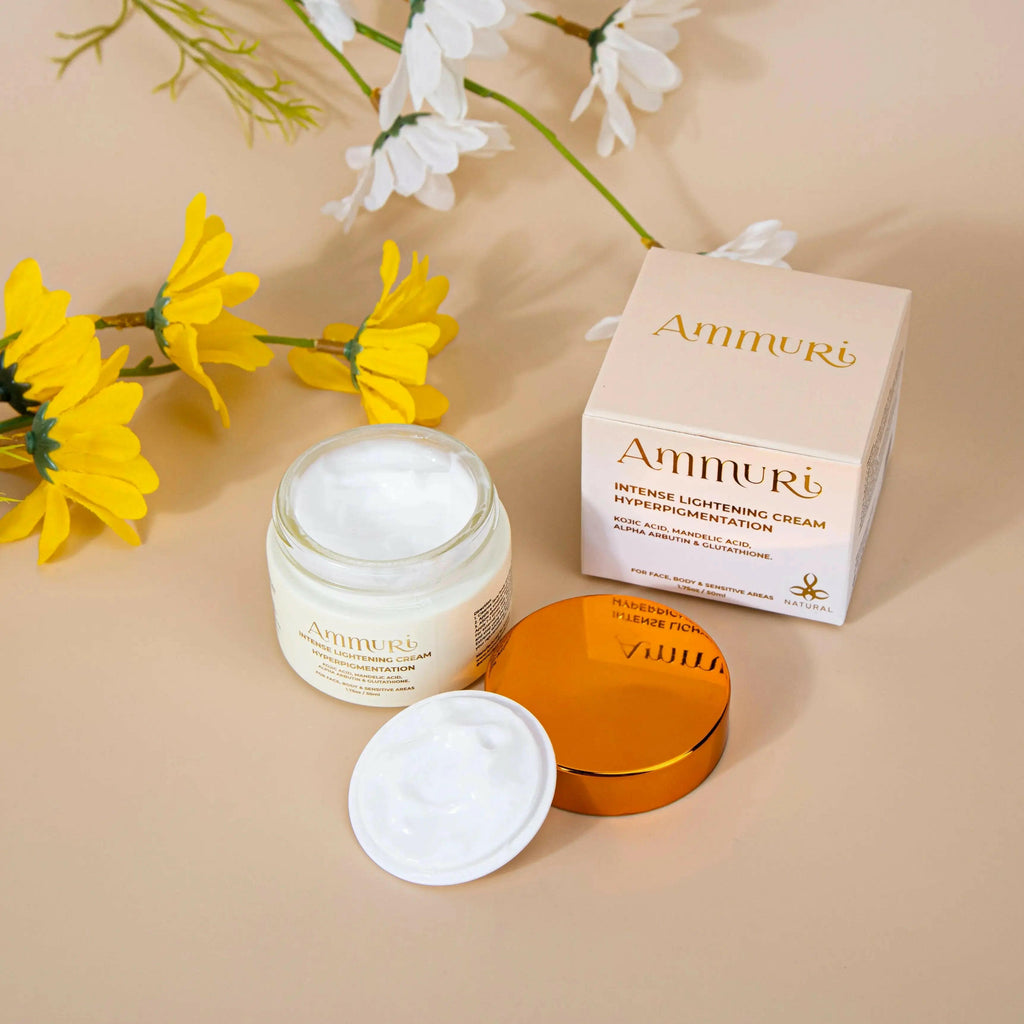 Ammuri Beauty skin lightening cream for dark spots in a jar with a golden lid next to its box and yellow flowers